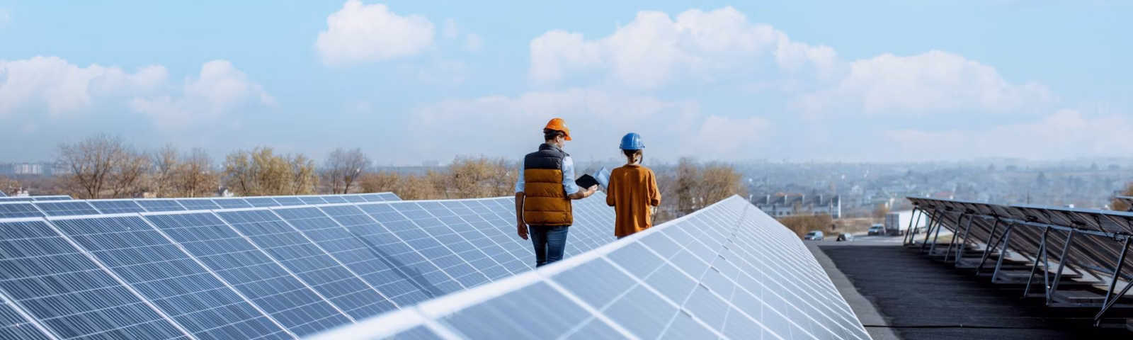 Zwei Mitarbeiter überprüfen eine Solaranlage auf einem Dach.