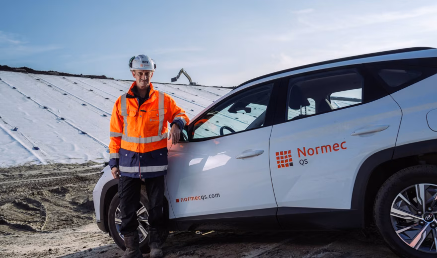 Een inspecteur staat bij een dienstvoertuig op locatie voor inspectie- en controlewerkzaamheden.
