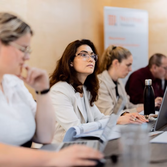 Teilnehmer einer geschäftlichen Schulung oder Veranstaltung arbeiten mit Laptops an einem Konferenztisch.