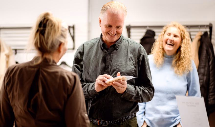 Bezoekers melden zich aan bij een ontvangstbalie terwijl een medewerker op een tablet gegevens controleert.