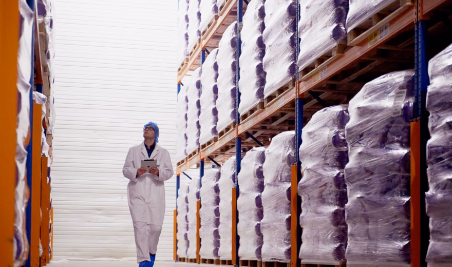 An employee checks products stored in a warehouse environment for quality and inventory management purposes.