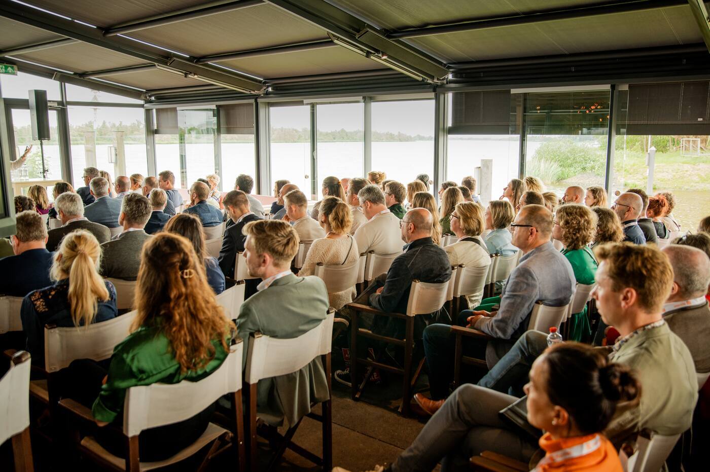 The audience is watching a presentation or knowledge session during a meeting in a conference or training room.