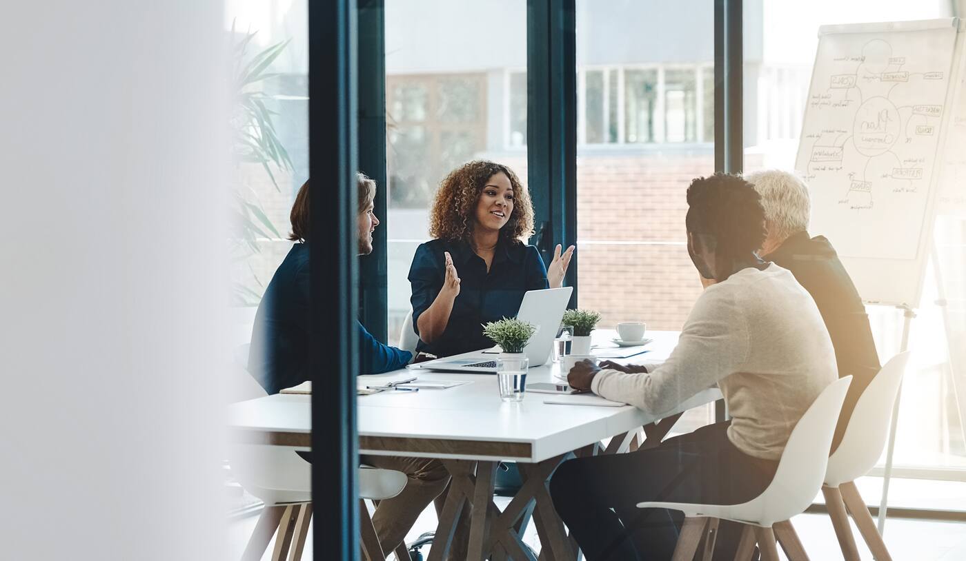 Colleagues meeting in a conference room, giving a presentation and collaborating at the table.