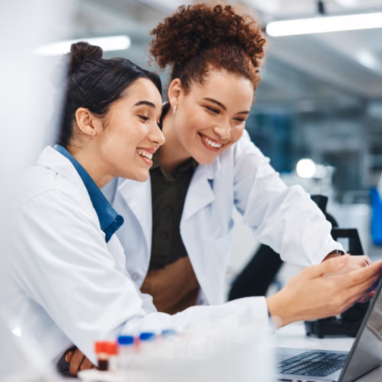Two lab technicians review results together on a laptop in a modern laboratory