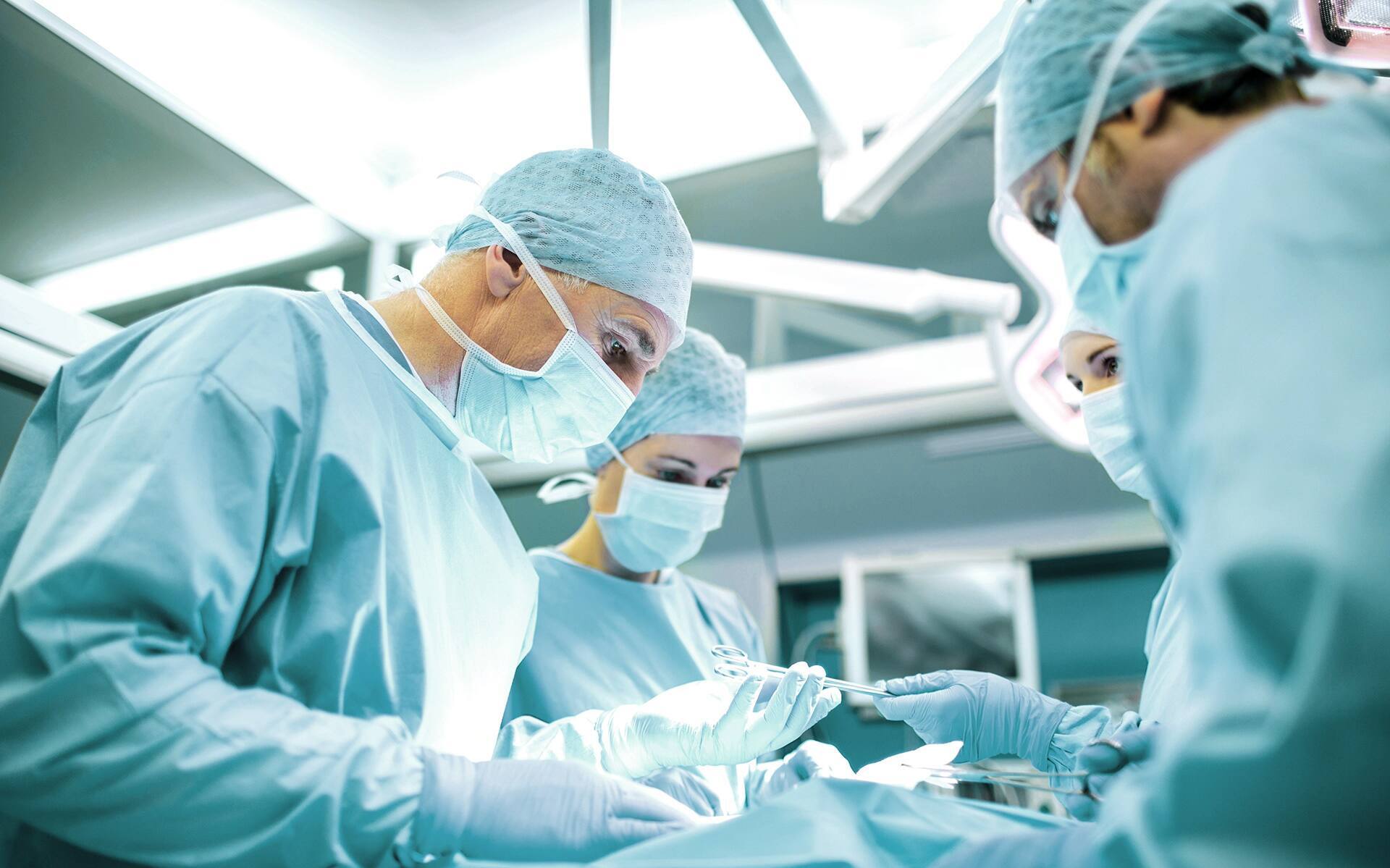 A surgical team performs surgery in a modern operating room equipped with sterile scrubs and medical equipment.