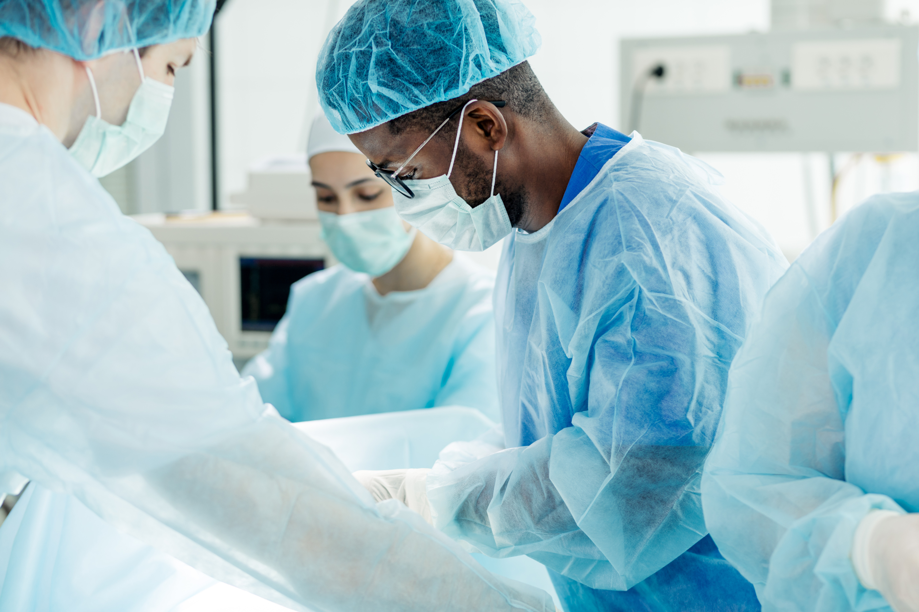 Healthcare professionals are performing a medical procedure in a sterile operating room.