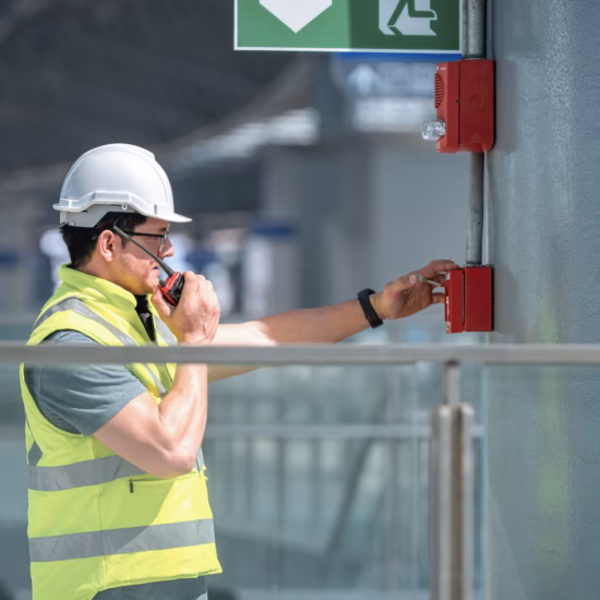 An employee tests a manual fire alarm as part of a fire alarm system in a building.