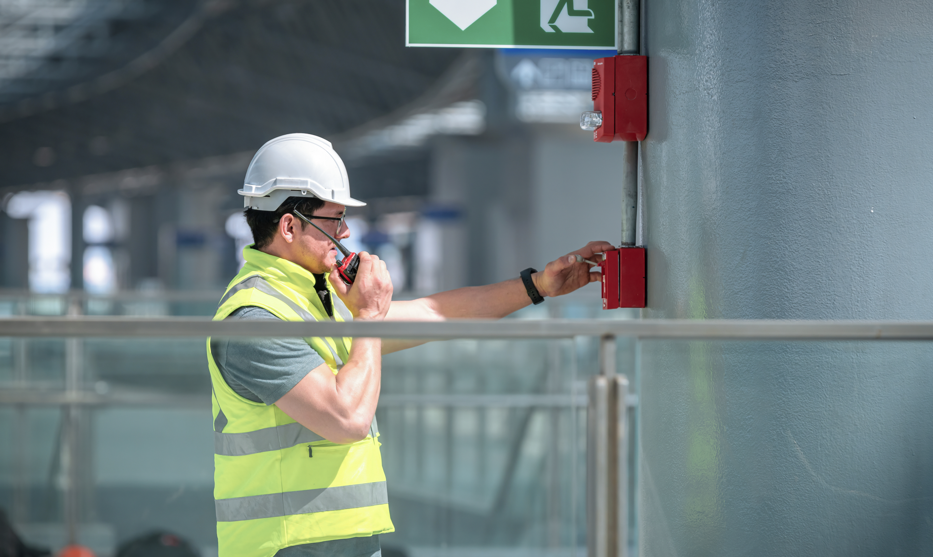 An employee tests a manual fire alarm as part of a fire alarm system in a building.