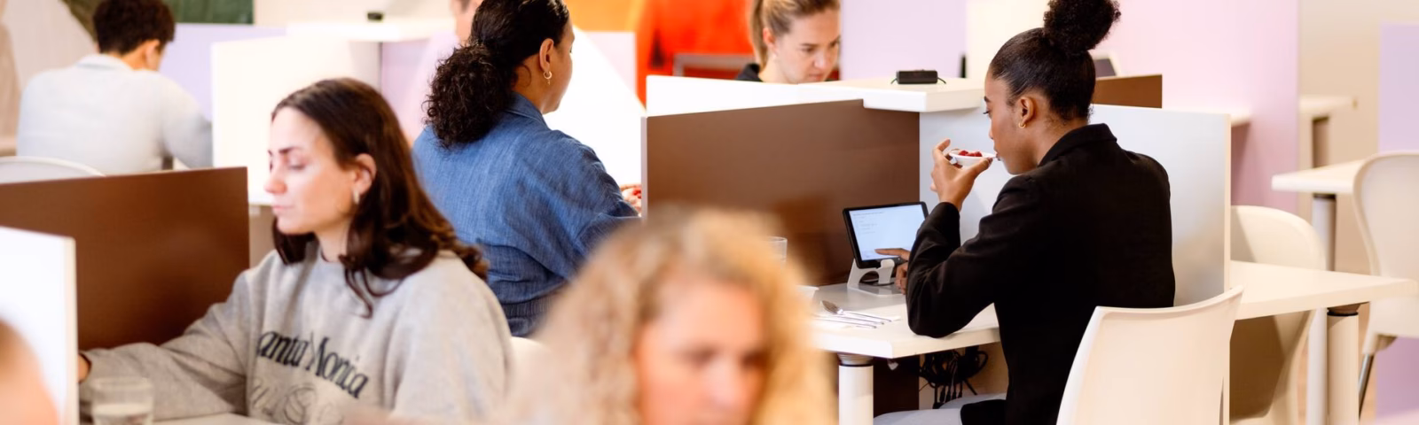 Die Mitarbeiter arbeiten an Computern in einer modernen Büroumgebung mit offenen Arbeitsplätzen und Rückzugsbereichen.