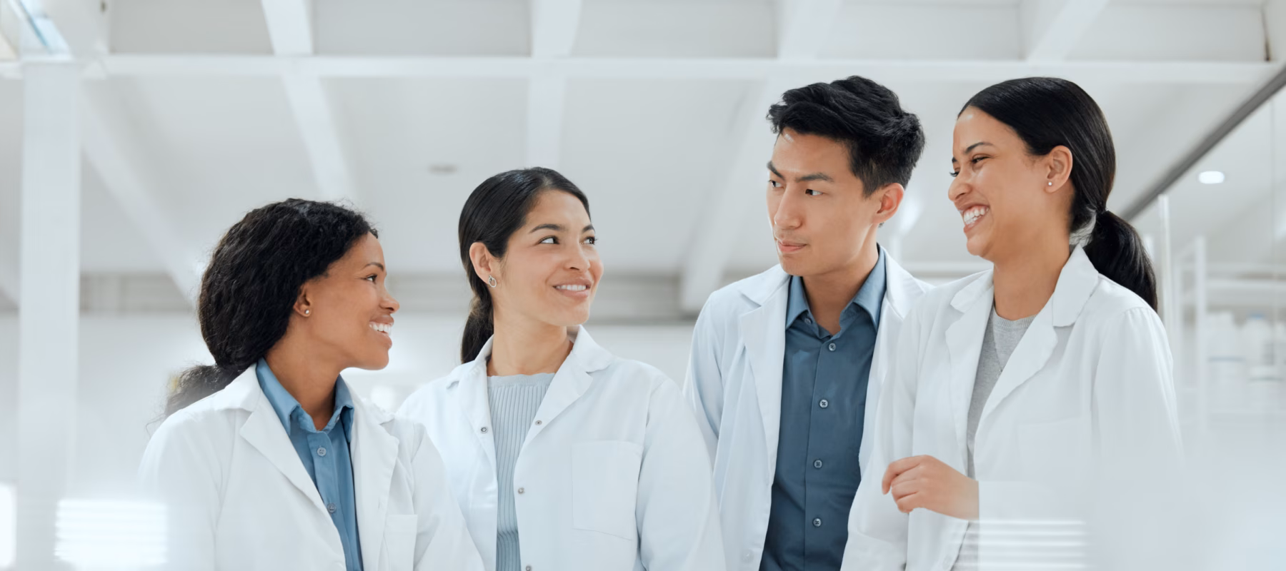 4 scientists in lab coats laughing in a laboratory