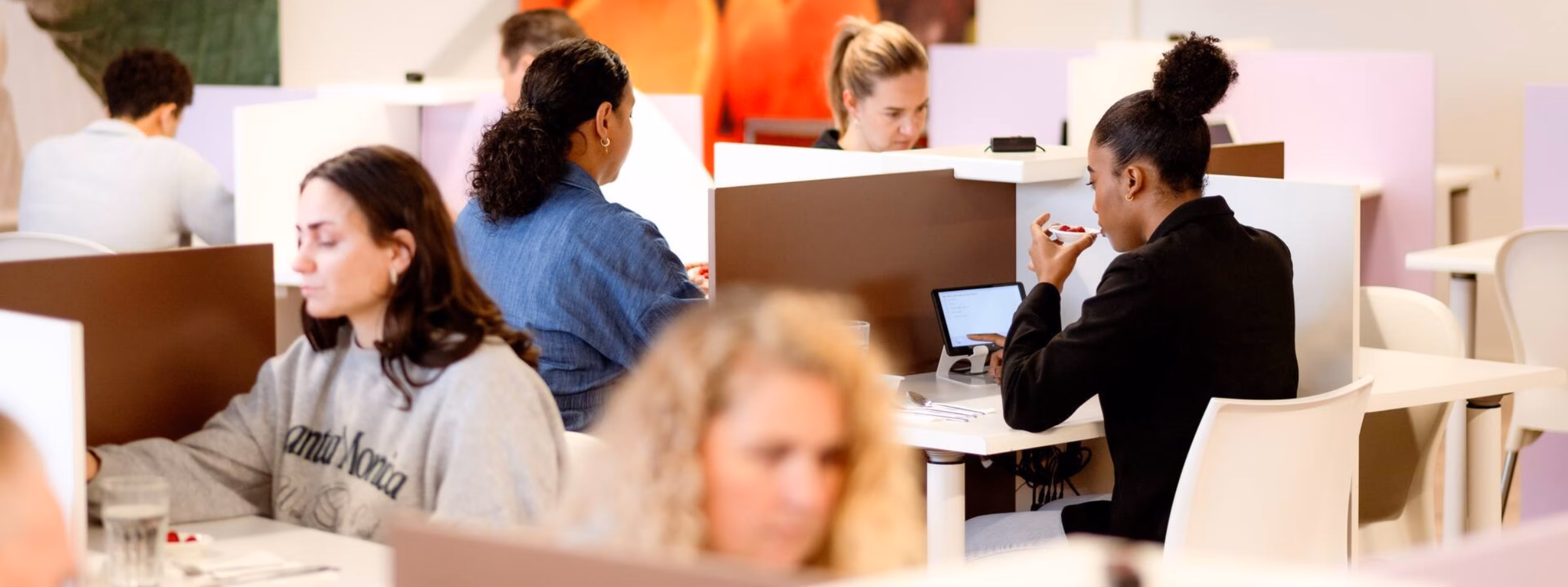 Employees work on computers in a modern office environment featuring open workspaces and quiet zones.