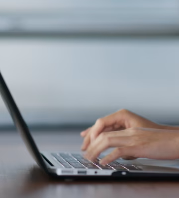 Handen typen op een laptop aan een bureau in een moderne werkomgeving