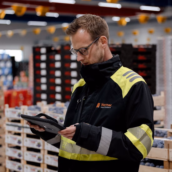 Magazijnmedewerker met handheld scanner controleert goederen in een logistieke omgeving.