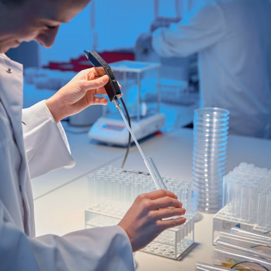 Een vrouwelijke onderzoeker in een wit laboratoriumjas analyseert een vloeistof in een reageerbuis tijdens een wetenschappelijk experiment.