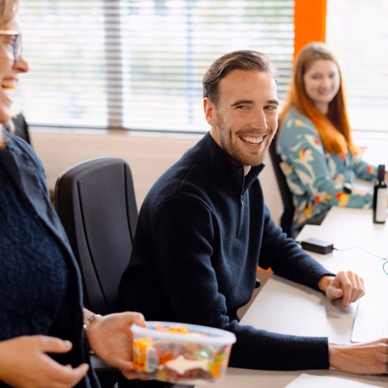Mitarbeiter arbeiten im Büro gemeinsam hinter Computerbildschirmen während einer Besprechung am Arbeitsplatz.
