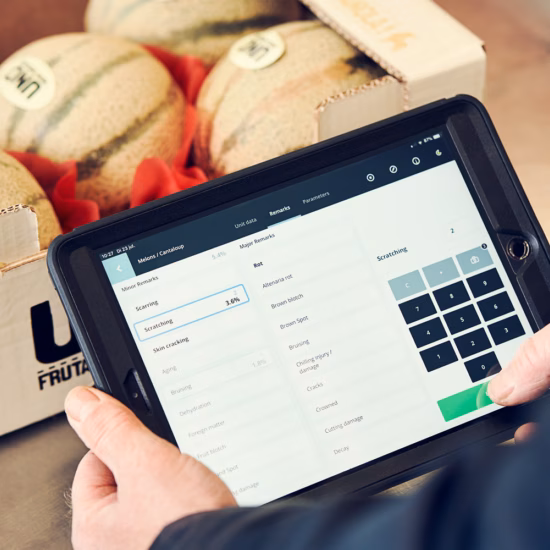 Tablet met digitaal formulier voor kwaliteitscontrole naast verpakte voedingsproducten in een productieomgeving.