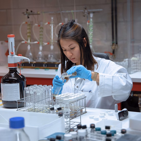 Ein Laborassistent führt in einem Untersuchungslabor eine Analyse mit einer Pipette und Reagenzgläsern durch.