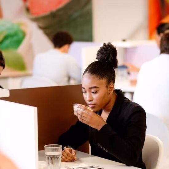 Two women are testing food in cubicles, with one woman smelling the food she is researching.
