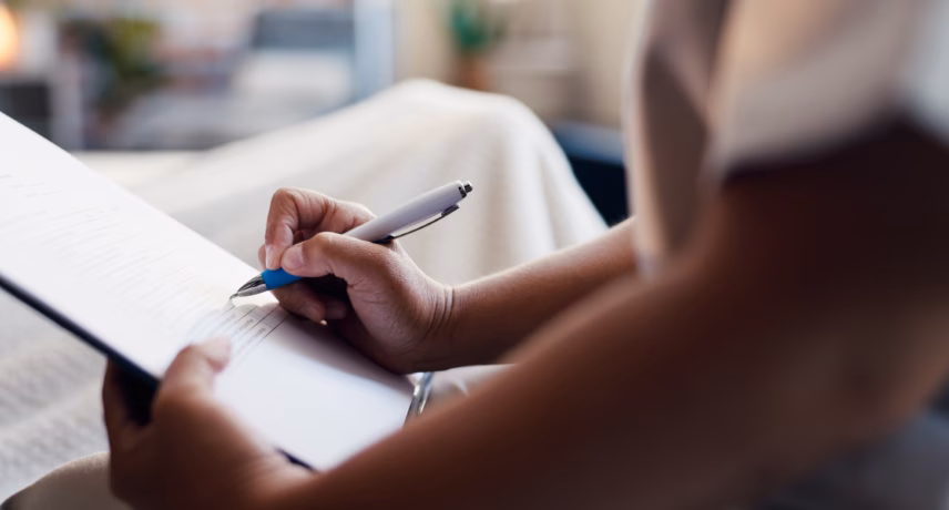 Persoon maakt aantekeningen op een formulier of checklist met een pen tijdens een inspectie, beoordeling of administratief proces.