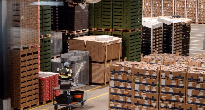 Magazijn met gestapelde pallets, kartonnen dozen en een autonome mobiele robot voor intern transport.