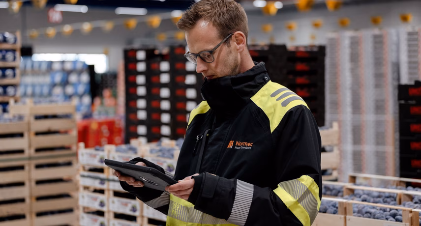 A warehouse worker with a handheld scanner checks goods in a logistics environment.