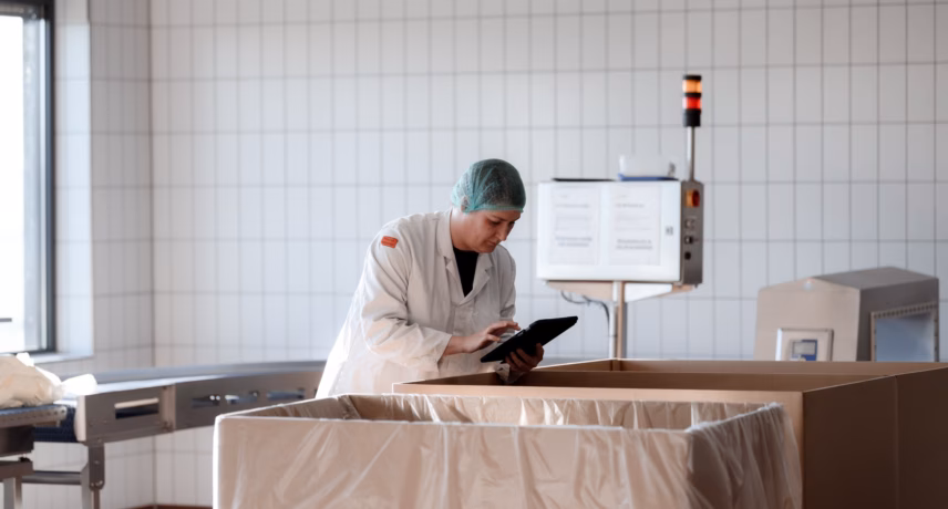 Medewerker voert kwaliteitscontrole uit in een steriele productieruimte met tablet.