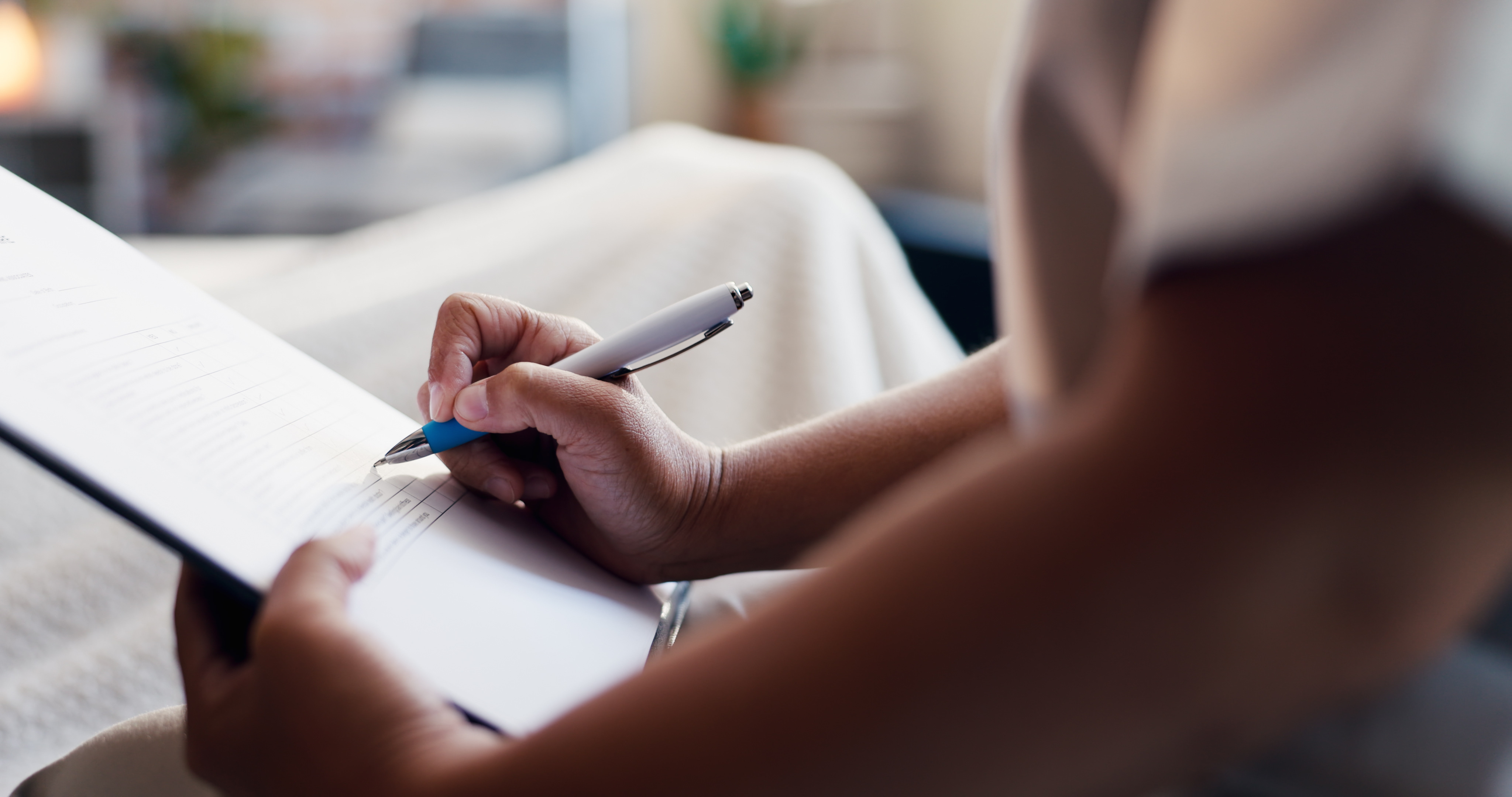 A person makes notes on a form or checklist with a pen during an inspection, assessment, or administrative process.