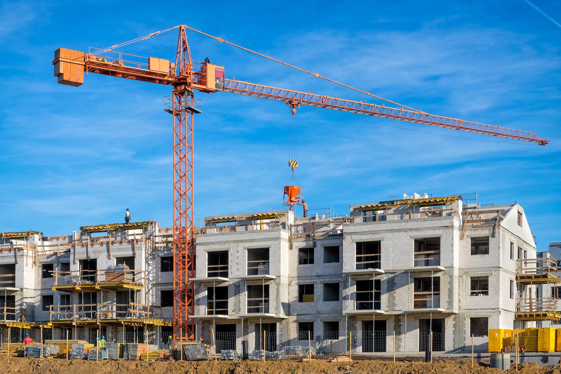 New construction project featuring apartment complexes under construction and a tower crane at an active construction site.