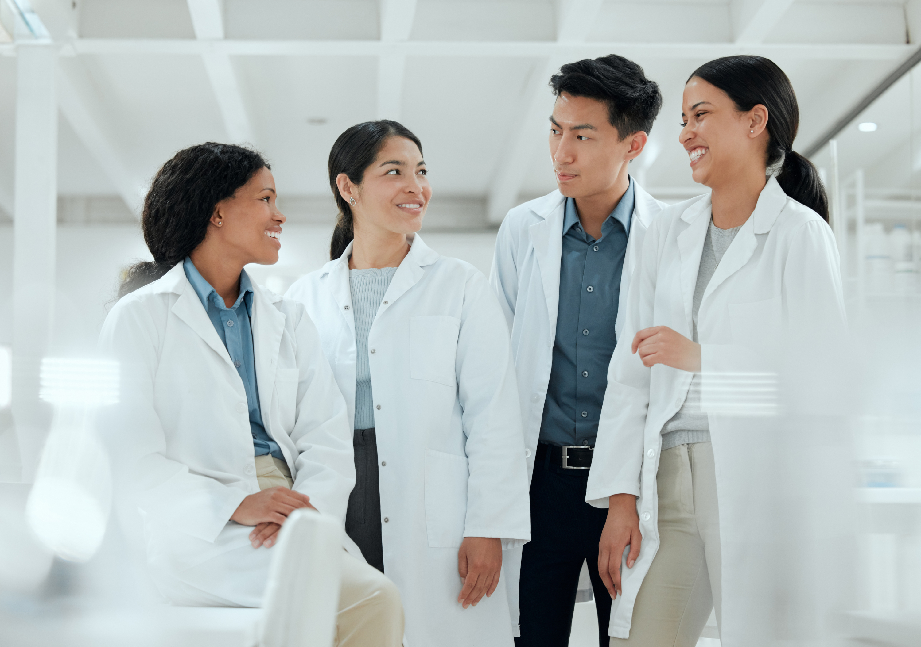 4 scientists in lab coats laughing in a laboratory